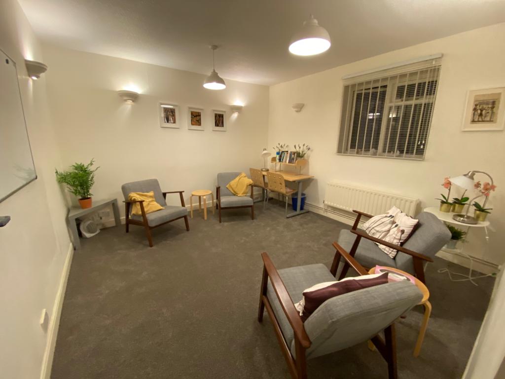 Spacious counselling room with lounge chairs, desk space, and warm lighting.