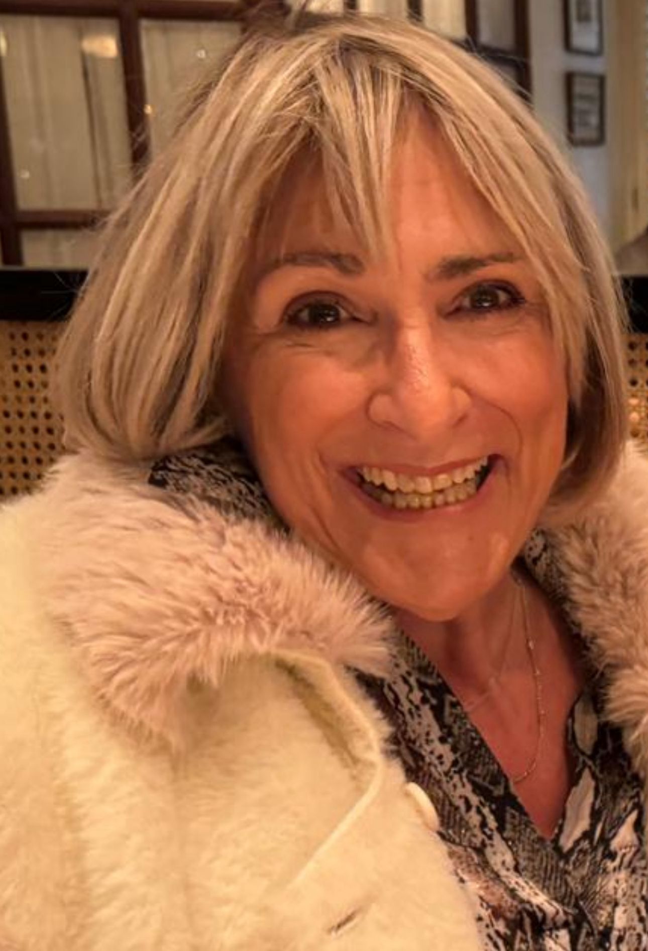 Portrait of a smiling woman in a cream coat.